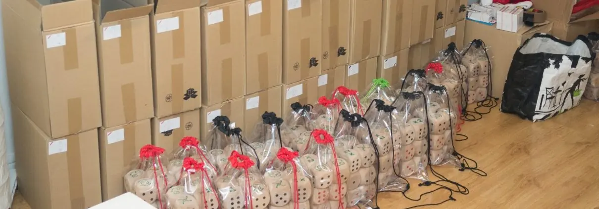 Les débuts du projet : cartons, sacs de jeux et piles de dés dans un appartement