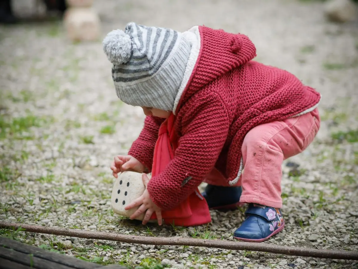 Jeune enfant qui ramasse une Caboule sur le gravier