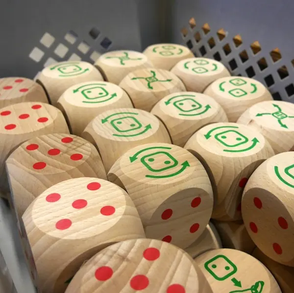 Caboules marquées de points rouges et de symboles verts, rangées dans une caisse à l'atelier