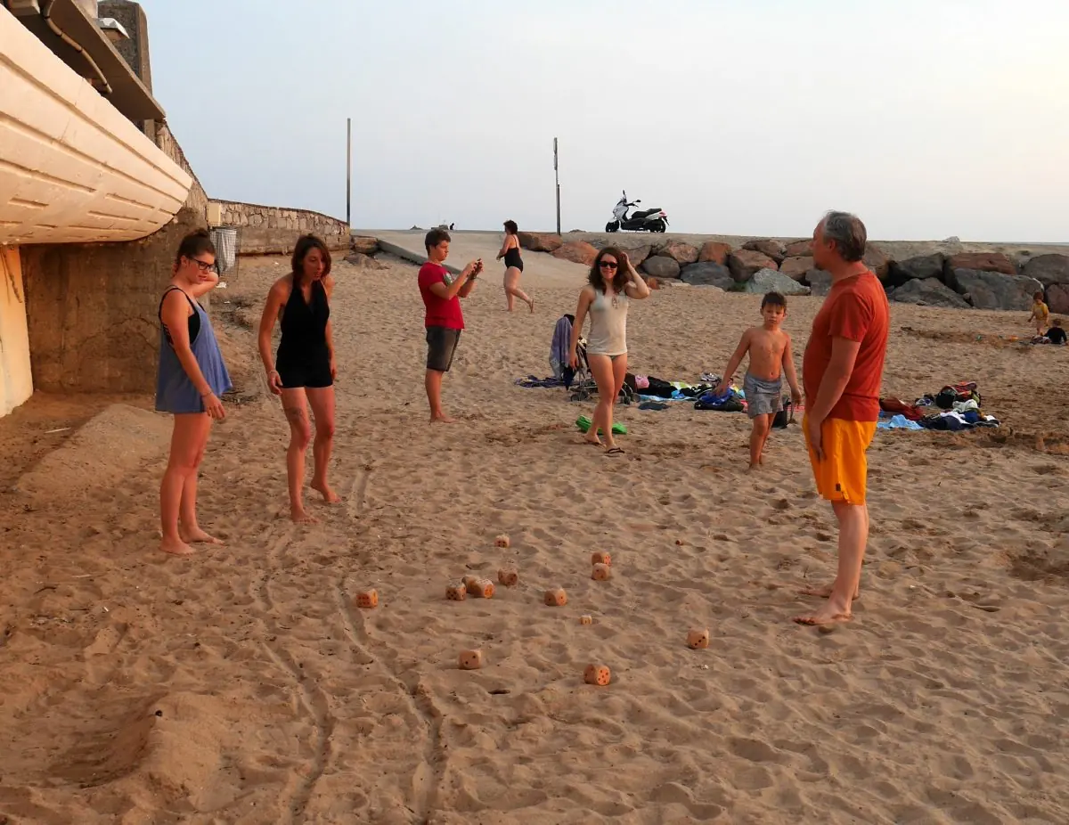 Partie de détanque en famille sur une plage au coucher du soleil